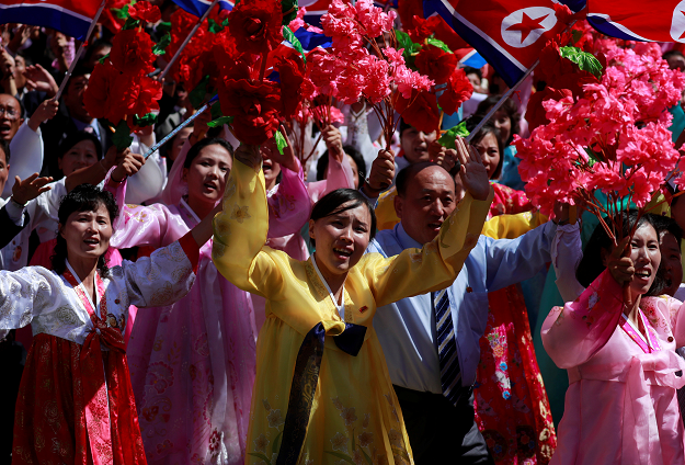 People wave plastic flowers during a military parade. PHOTO:REUTERS