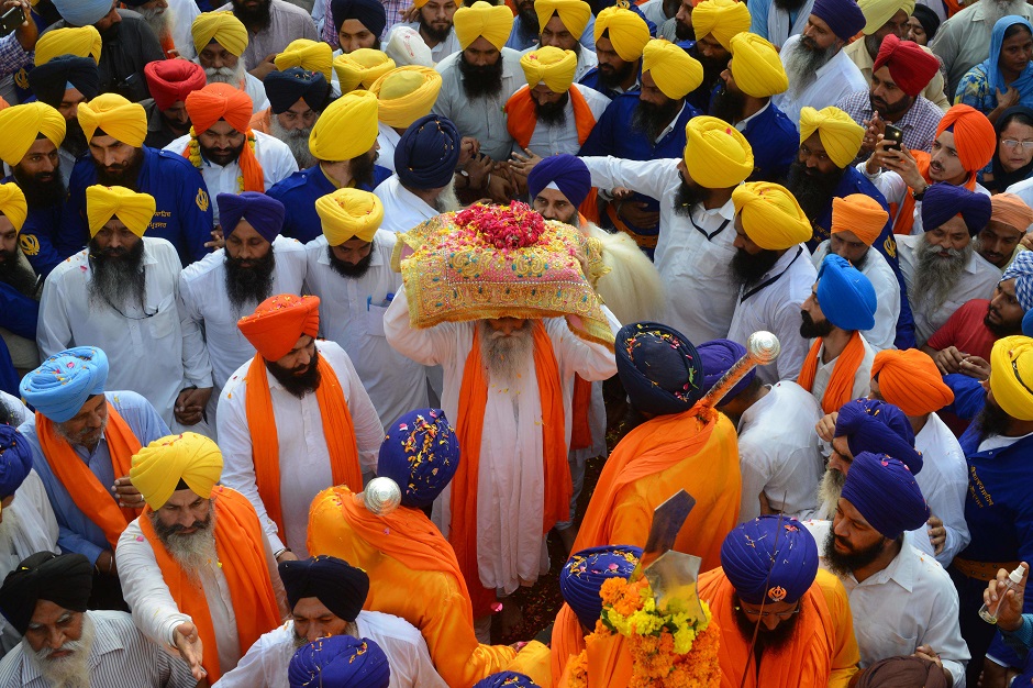 Indian Sikh priest Giani Jagtar Singh (C) carries the Guru Granth Sahib, the central religious text of Sikhism, during a religious procession from Gurudwara Ramsar to Akal Takht Sahib to mark the 414th anniversary of the installation of the Guru Granth Sahib at the Golden Temple in Amritsar on September 10, 2018. PHOTO: AFP