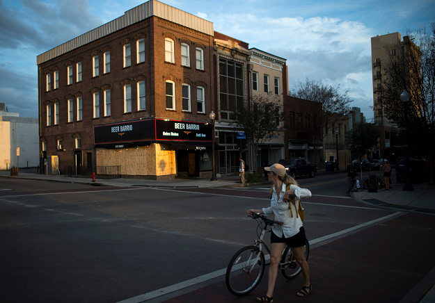 A woman walks her bike across a street near a boarded up bar a day before the arrival of Hurricane Florence in Wilmington. PHOTO:AFP