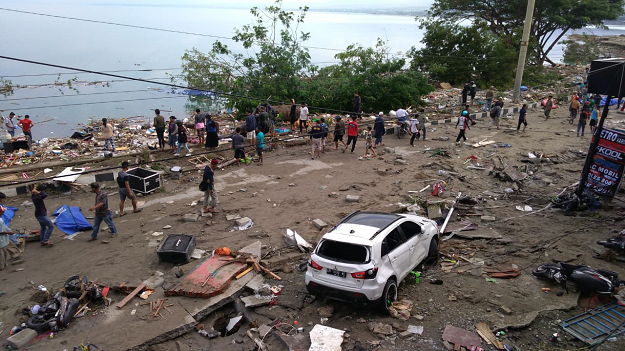 People walk past dead bodies a day after an earthquake and a tsunami hit Palu. PHOTO: AFP