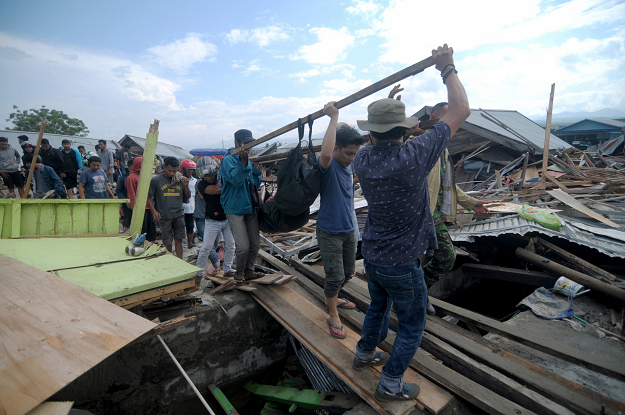Residents helping remove a body after an earthquake and tsunami hit Palu. PHOTO: AFP