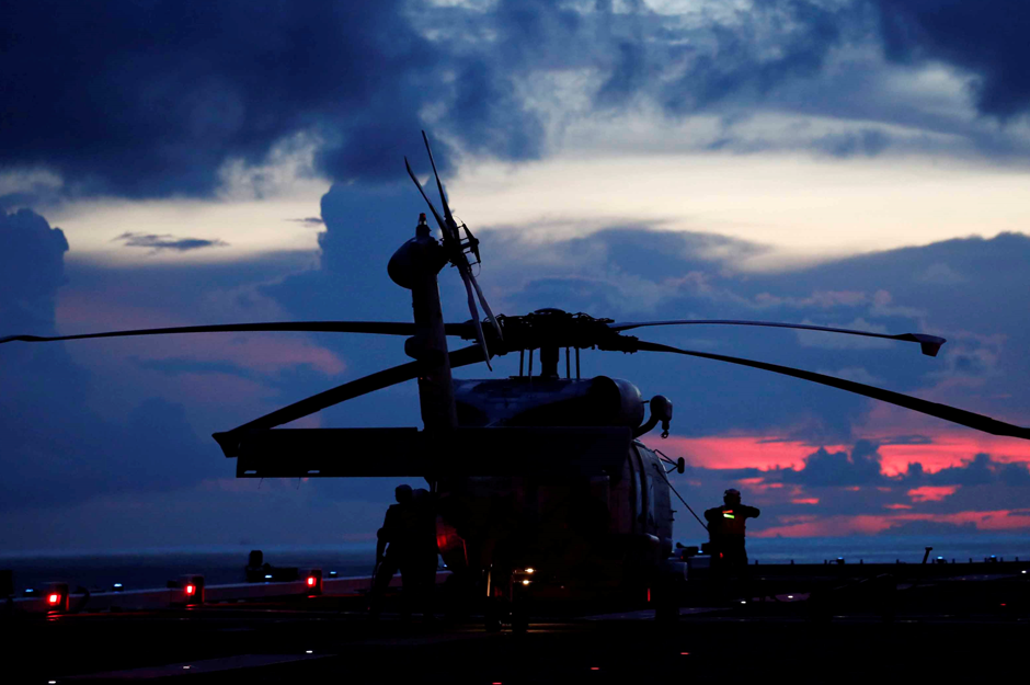 An SH-60K Sea Hawk helicopter on the flight deck of Japanese carrier Kaga is silhouetted against the sky after a joint drill with a British frigate in the Indian Ocean. Reuters