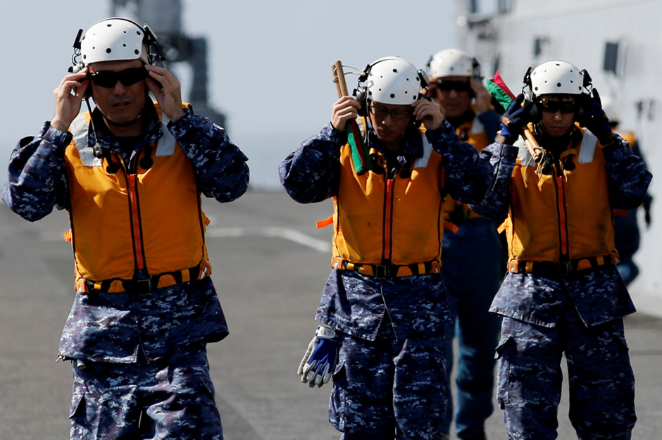 Maintenance crew walk toward an SH-60K Sea Hawk helicopter on Japanese carrier Kaga taking part in a joint naval drill with a British frigate in the Indian Ocean. Reuters