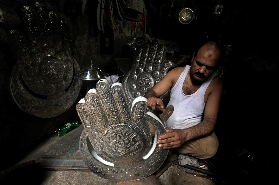 A man shapes a religious symbol for sale in preparation for the Ashura procession in Lahore on September 11, 2018. PHOTO:REUTERS