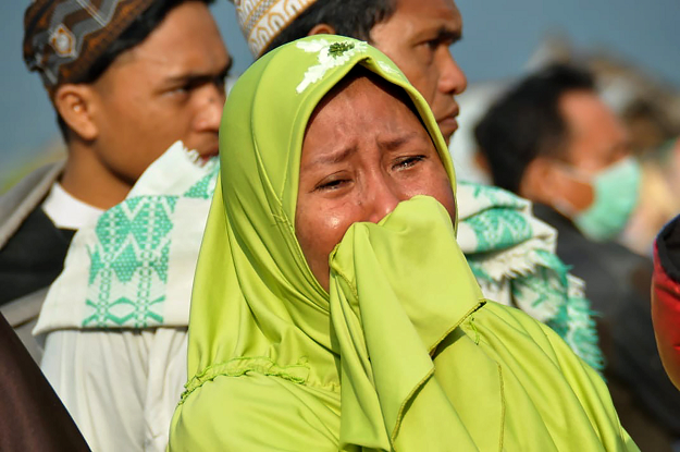 A woman cries as people look at the damages after an earthquake and a tsunami hit Palu AFP