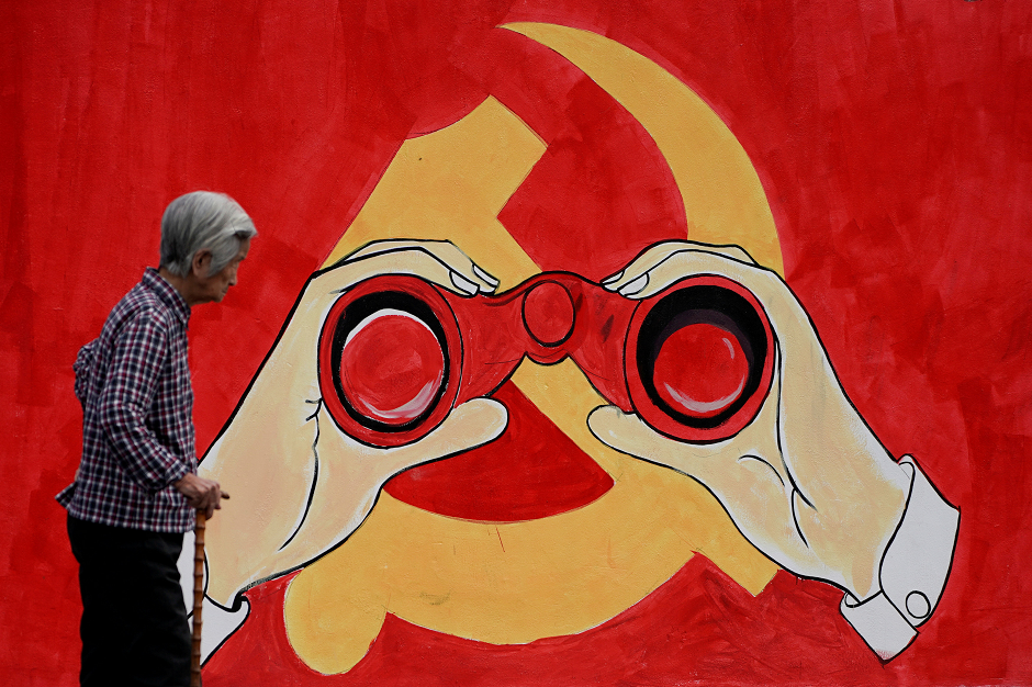 A woman stands near a mural showing an emblem of the Communist Party of China along a street in Shanghai, China  Reuters