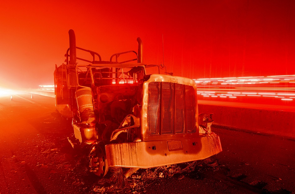 A fire vehicle passes by an abandoned burned out truck along interstate 5 after the Delta Fire tore through the region and jumped the road in Delta, California. PHOTO: AFP