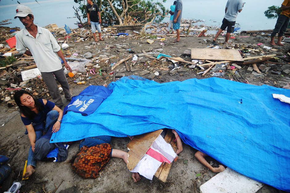 Residents looking at covered up bodies recovered after an earthquake and tsunami. PHOTO: AFP
