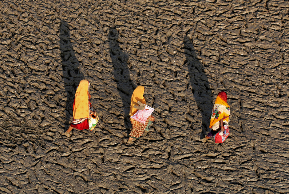  Women walk on the muddy banks of the Ganges river after taking a holy dip, in Allahabad, India, Reuters