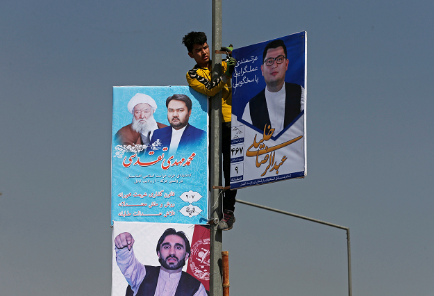  A man installs election posters of parliamentary candidates during the first day of election campaign in Kabul. PHOTO: REUTERS