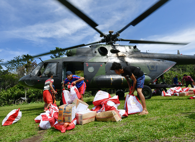 Indonesian villagers offloaded aid from a military helicopter in Proo village. PHOTO: AFP