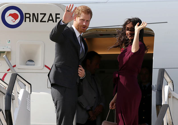 Britain's Prince Harry and his wife Meghan, Duchess of Sussex wave as they board an aeroplane at the airport in Sydney. PHOTO: AFP