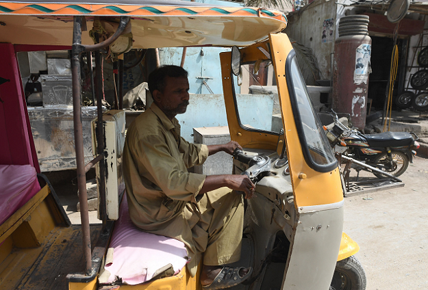 Auto-rickshaw driver Mohammad Rasheed drives his rickshaw in Korangi. PHOTO: AFP