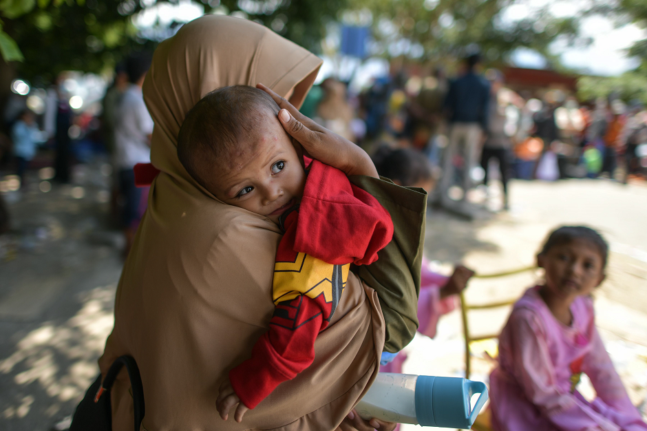 A mother consoles his son as they wait to board military airplanes for evacuations at the Mutiara SIS Al Jufrie Airport in Palu AFP