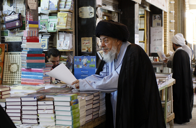 A Muslim religious man stands a shop at the Howeish book market in the holy city of Najaf AFP