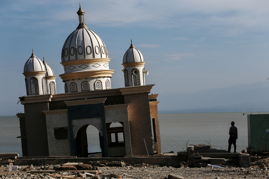 A police officer stands next to the remains of a mosque destroyed by the earthquake and tsunami in Palu, Central Sulawesi, Indonesia REUTERS