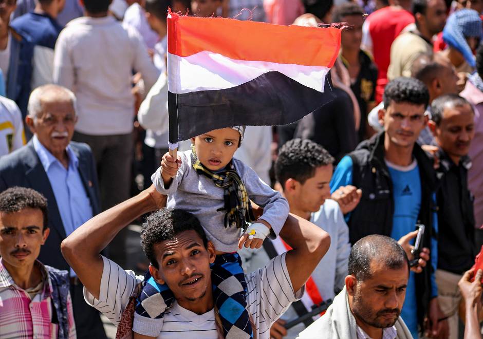 A Yemeni man holds a child on his shoulder waving the Yemeni flag as they march during a protest against inflation in Taez. PHOTO: AFP