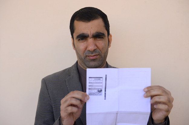 Afghan public servant Ghulam Farooq Adil poses for a picture as he holds his id card or Tazkira in Herat province. PHOTO: AFP