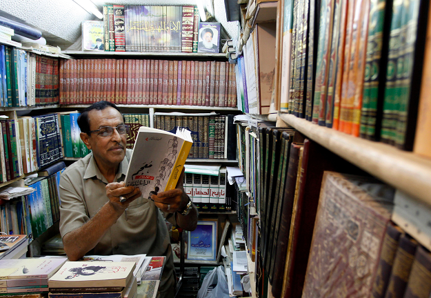 An Iraqi man reads a book at a shop in the Howeish book market AFP