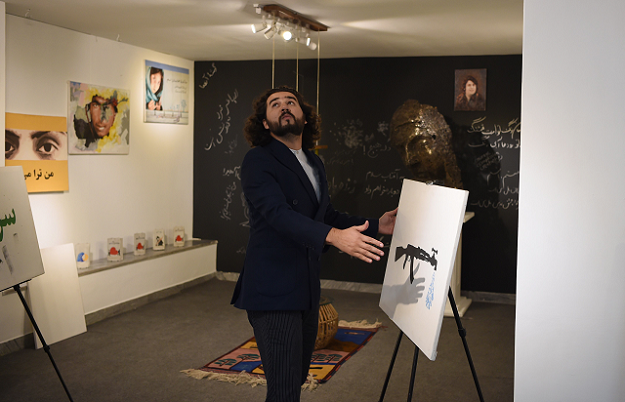 Co-founder and president of ArtLords, Omaid Sharifi places a painting after he registered to vote, in Kabul. PHOTO: AFP