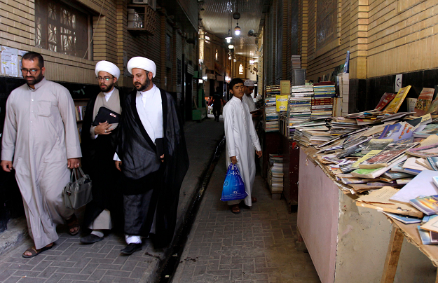 Iraqi Muslim religious men walk at the Howeish book market. PHOTO: AFP