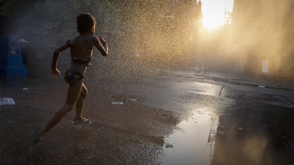 A young girl runs through a sprinkler at a playground. PHOTO: REUTERS