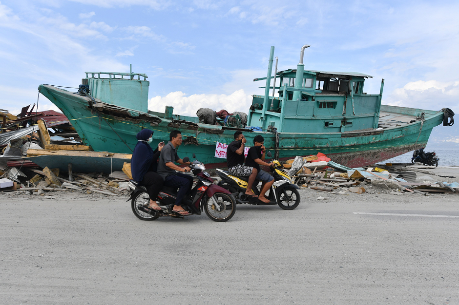 Motorists drive past an upside down boat in Mamboro, Indonesia's Central Sulawesi  AFP
