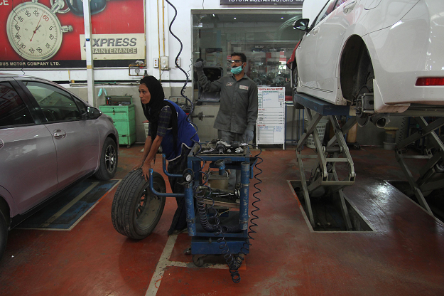 Nawaz, 24, rolls a tyre as she fixes a car. PHOTO: AFP