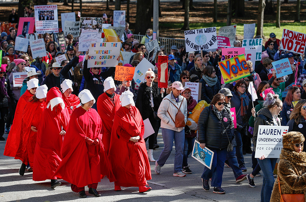 People hold signs next to women dressed as characters from 'The Handmaid's Tale'. PHOTO: AFP