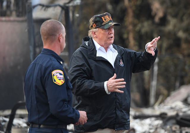 US President Donald Trump speaks with a fire fighter as he tours an area destroyed by a wildfire in Malibu. PHOTO: AFP