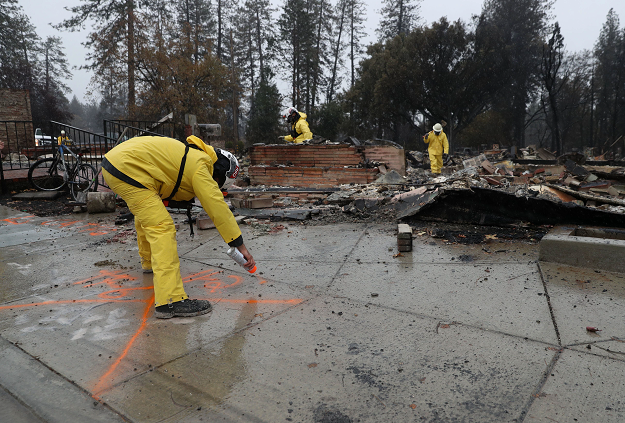  Search and rescue crews dig through the burnt remains of a business as they search for human remains. PHOTO: AFP