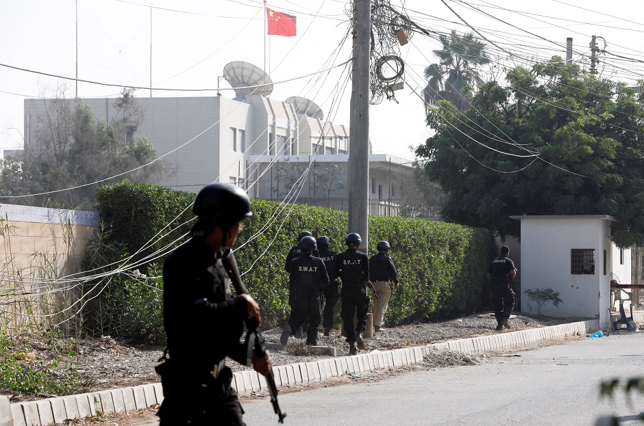 Police officers take cover as they move during an attack on the Chinese consulate. PHOTO: REUTERS