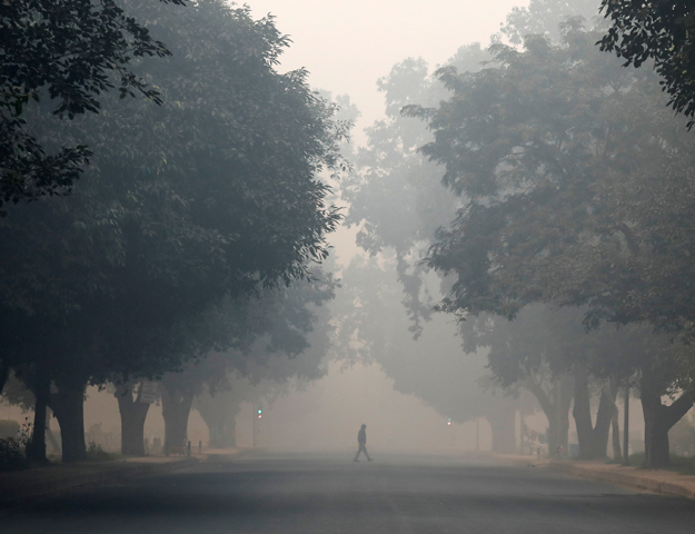 A man crosses a road on a smoggy morning in New Delhi, India, November 8, 2018. REUTERS