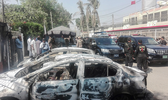 Security personnel stand next to burned out vehicles in front of the Chinese consulate after an attack. -Photo: AFP