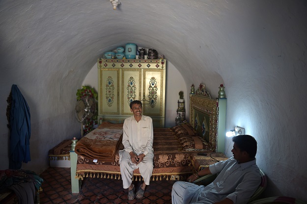 Ameer Ullah Khan chats with a friend in his cave room in Nikko village PHOTO: AFP
