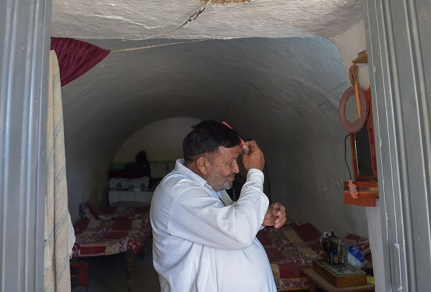 Haji Abdul Rasheed combs his hair at the entrance to his cave room PHOTO: AFP