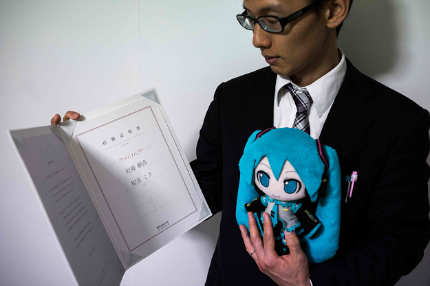 In this photograph taken on November 10, 2018 Japanese Akihiko Kondo poses with a doll of Japanese virtual reality singer Hatsune Miku, as he shows their marriage certificate, at his apartment in Tokyo, a week after marrying her. PHOTO: AFP