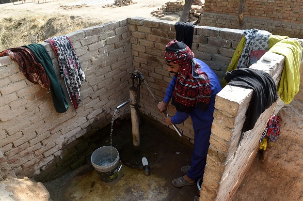 In this picture taken a Pakistani man pumps water at a hand pump next to a toilet in Basti Ameerwala village in central Punjab province. PHOTO: AFP