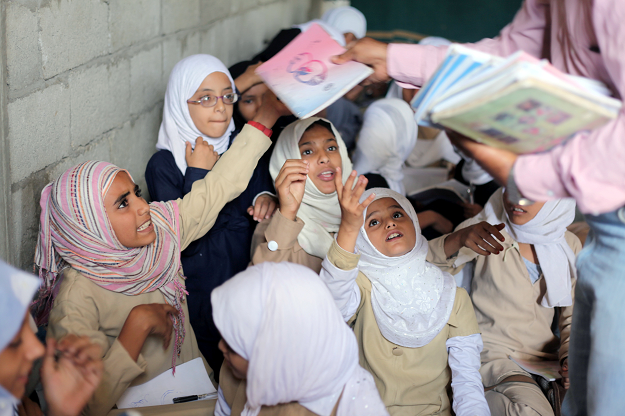 Students receive books in their class at the teacher's house, who turned it into a makeshift free school that hosts 700 students, in Taiz, Yemen October 18, 2018. PHOTO: REUTERS