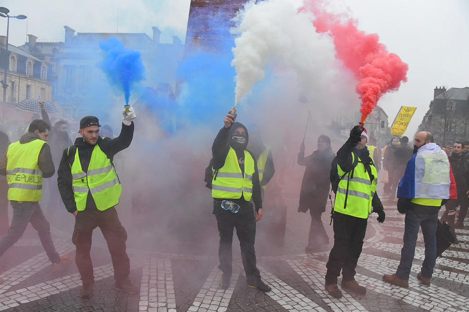 Protestors light flares in the colours of the French flag during a 