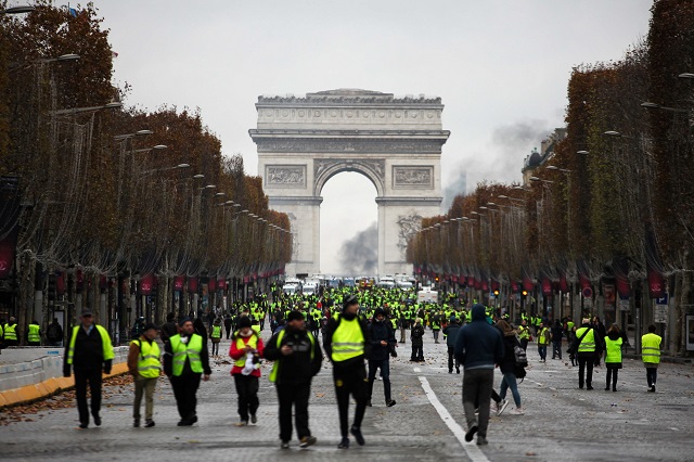 demonstrators walk near the arc de triomphe during a protest of yellow vests gilets jaunes against rising oil prices and living costs on december 1 2018 in paris photo afp