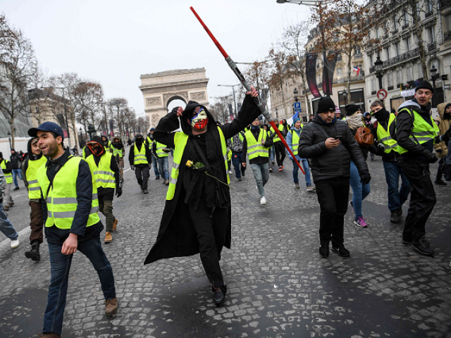 A man wearing an Anonymous mask and a yellow vest (gilet jaune) and holding a Star Wars Jedi light laser takes part in a demonstration to protest against rising costs of living they blame on high taxes, by the Arc de Triomphe in Paris, on December 15, 2018. PHOTO: AFP