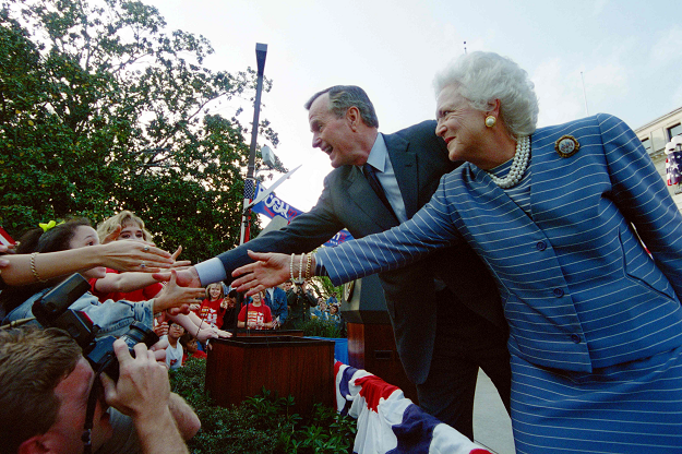 Former US President George Bush and Former First Lady Barbara Bush shake hands with members of the crowd at a 