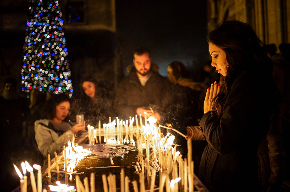 A woman prays as worshippers light candles during Christmas Mass at Saint Antuan Church in the Beyoglu district of Istanbul. PHOTO: AFP