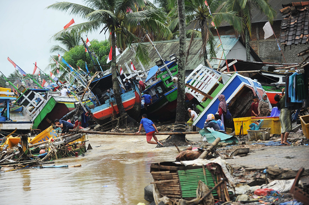 Fishermen tend to their traditional fishing boats which were damaged after being hit by a tsunami in the Teluk village. PHOTO: AFP