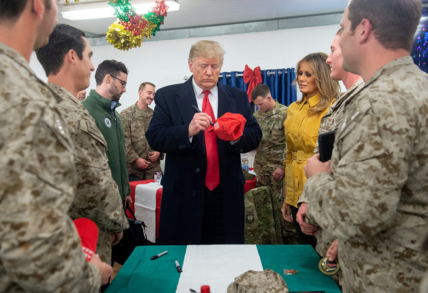 US President Donald Trump signs a hat as First Lady Melania Trump looks on as they greet members of the US military during an unannounced trip to Al Asad Air Base in Iraq. PHOTO: AFP