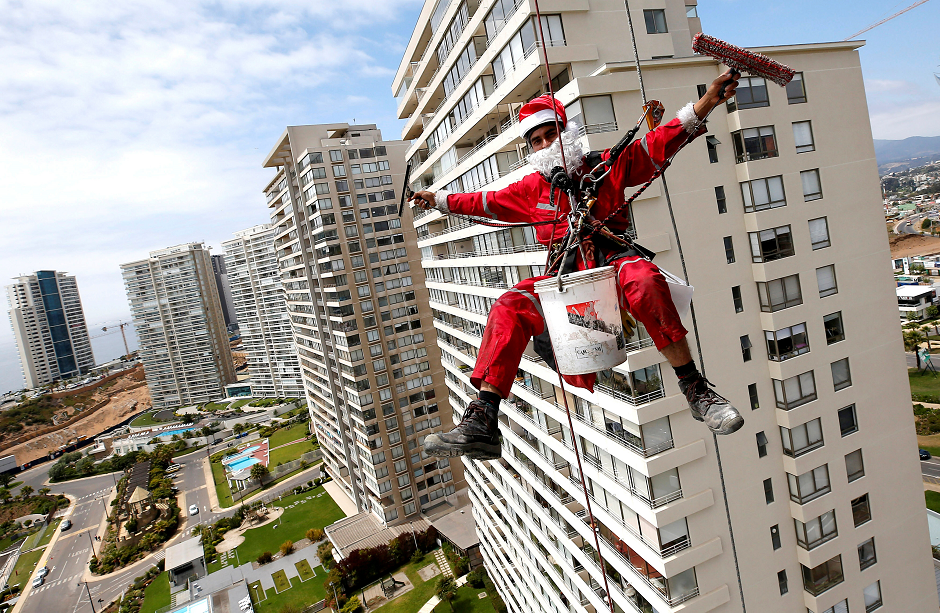 A worker waves as he cleans the windows of a building, dressed as Santa Claus, in Concon, Chile  December 22, 2018. PHOTO: REUTERS