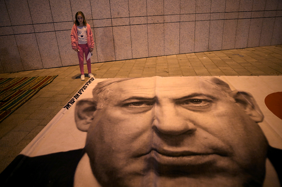 An Israeli girl stands next to a placard with the photo of Israeli Prime Minister Benjamin Netanyahu during a protest against the high cost of living in the centre of Tel Aviv, Israel December 22, 2018. PHOTO: REUTERS