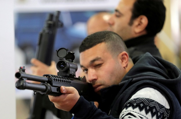 8.A visitor holds a weapon at the Saudi stand during on the first day of Egypt Defense Expo PHOTO: AFP