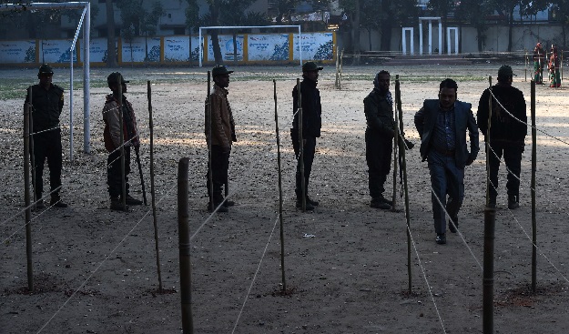 A Bangladeshi man walks past security members to cast his vote at a polling station in Dhaka. PHOTO: AFP